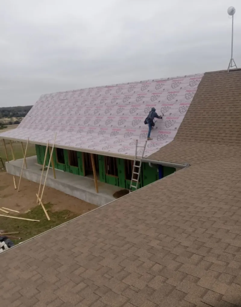 Worker preparing underlayment for a metal roof installation in Winter Beach
